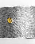 Flat-lay of the Reptilia Maxima silver cuff with yellow aragonite cabochon and snake-scale texture.