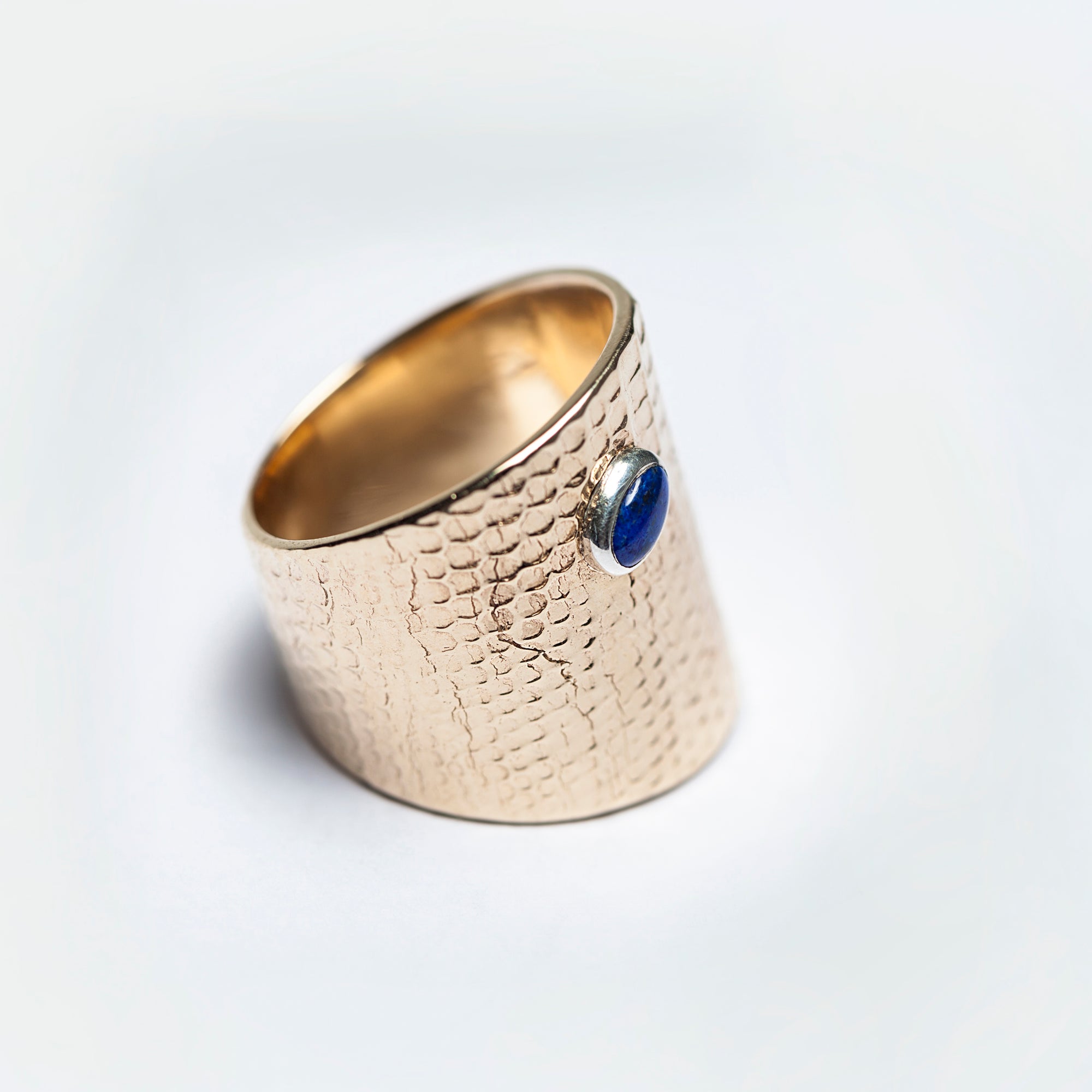 Three-quarter view of the Reptilia gold ring, bezel-set natural gemstone visible.